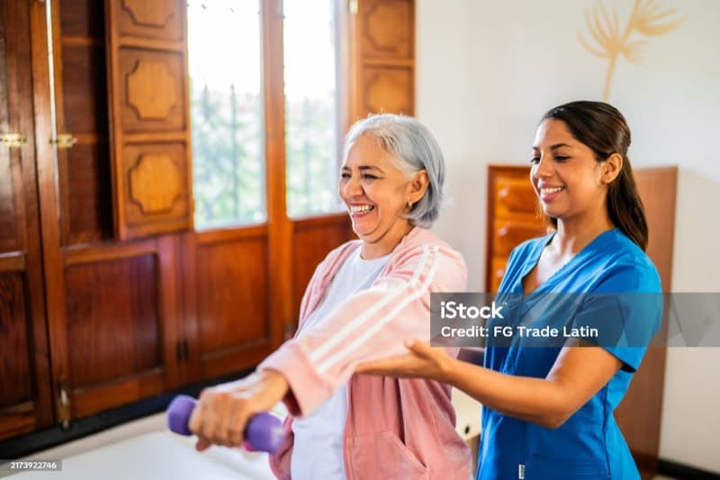 Physiotherapist working with a patient in their living room